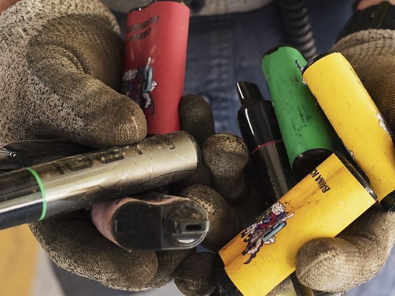 gloved hands holding a collection of used vapes