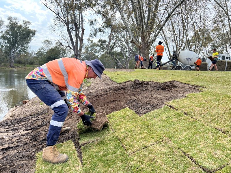 Man laying turf near river