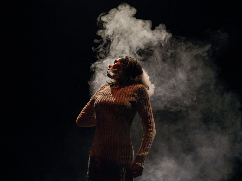 Female performer on stage shrouded twists her body